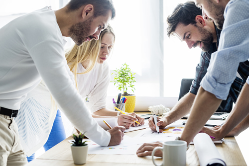 Photo of group of young entrepeneurs standing around a work table.